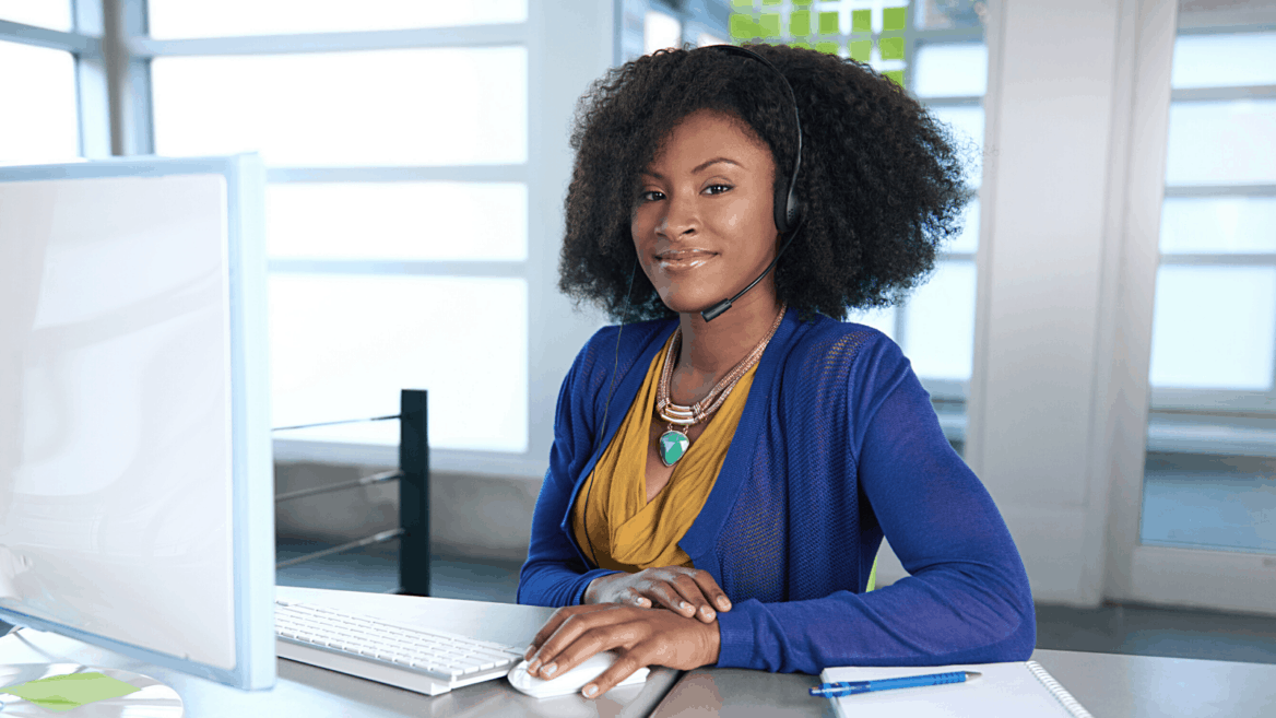 young african american woman working from home in a blue sweater and yellow blouse