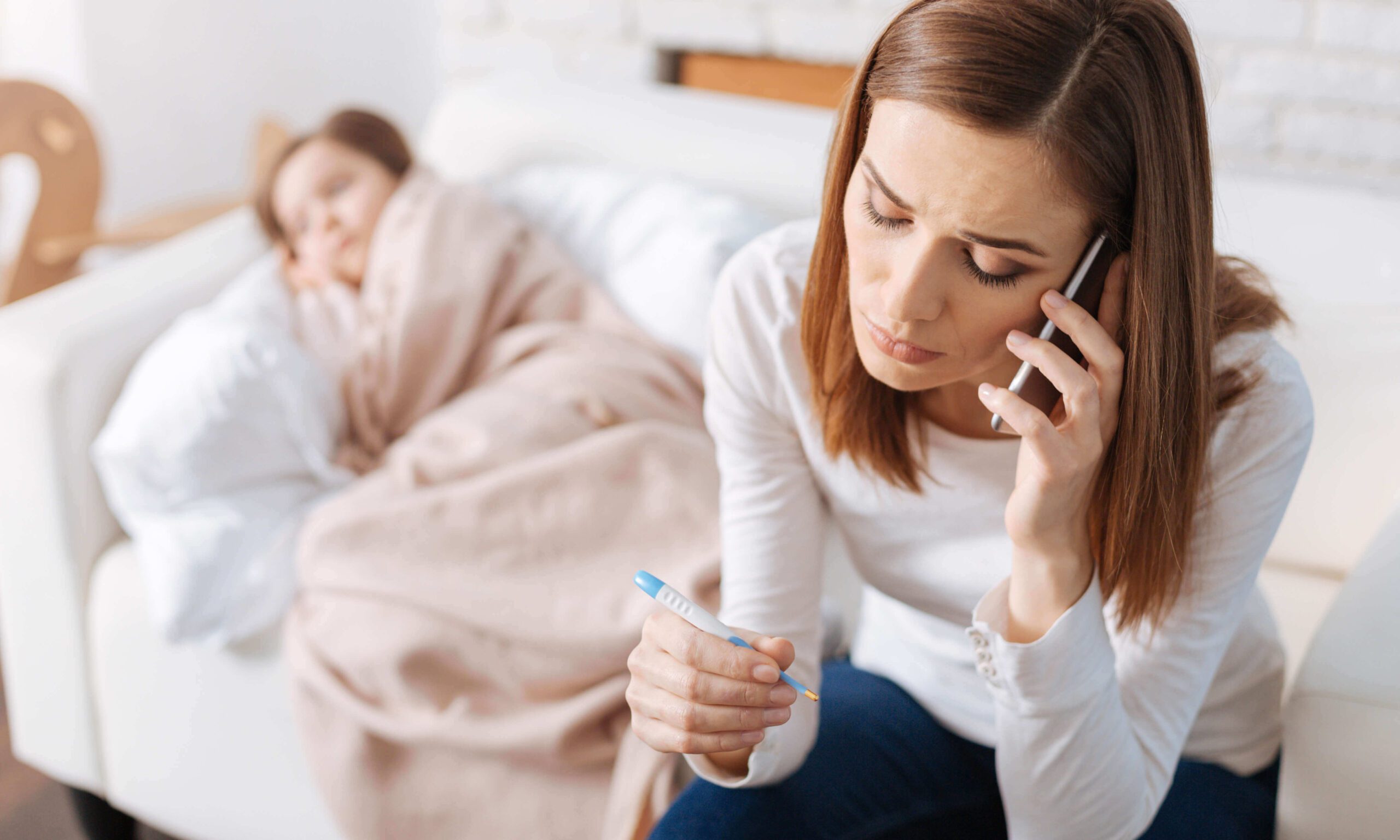 Image of sick child and worried mother talking to a healthcare agent.